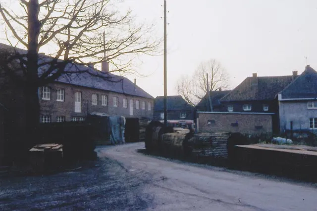 Historische Aufnahme: Straße in Ringenberg mit der alten Werkstatt und gestapeltem Holz